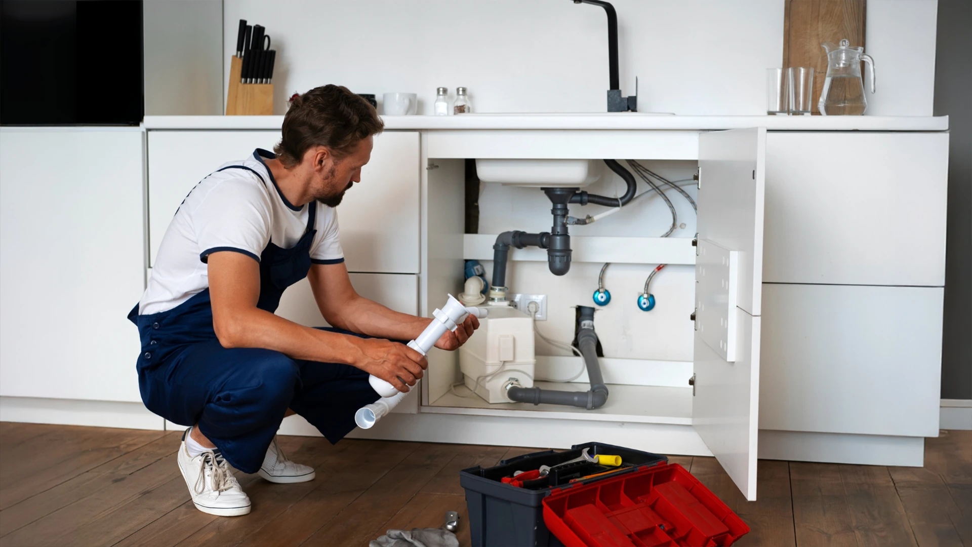 Plumber inspecting kitchen sink pipes as part of plumbing services in Dubai.