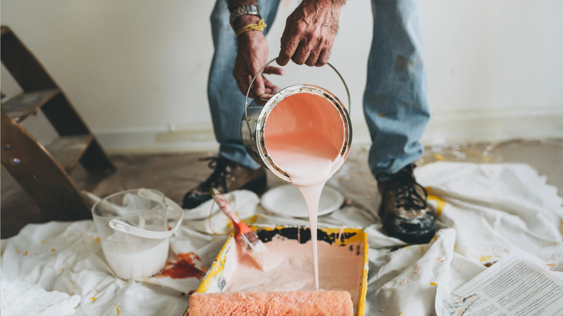 Painter pouring paint into a tray for interior wall painting services in Dubai.
