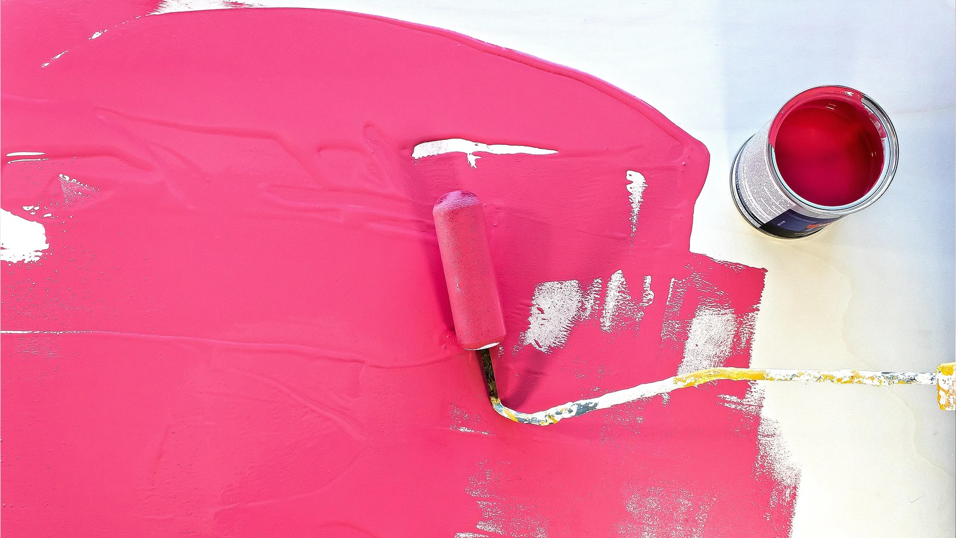 Close-up of vibrant pink paint being rolled on a wall as part of wall painting services in Dubai.